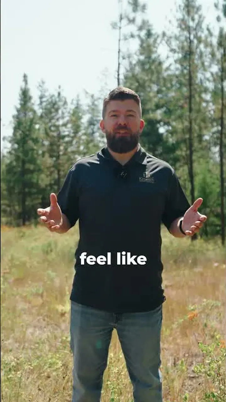 A man standing in an open meadow on the property with his arms out.